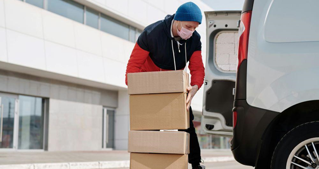 A man wearing a face mask and carrying boxes